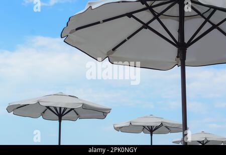 Beautiful white beach umbrellas against blue sky Stock Photo