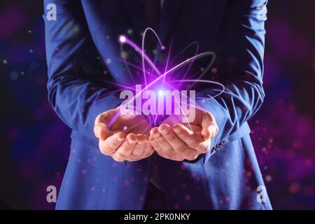 Man holding virtual model of atom on color background, closeup Stock Photo