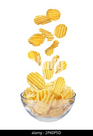 Ridged crispy potato chips falling into bowl on white background Stock Photo