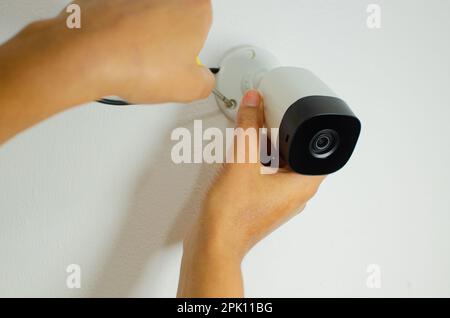 Technician installing CCTV camera security system. CCTV videocam, CFTV security camera, white camera with secure circuit, theft protection. Surveillan Stock Photo