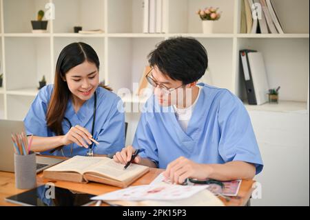 Two smart young medical students are studying and researching medical information at the library together. Stock Photo
