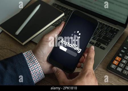 man installing Software Update On Mobile Phone And Laptop digital technology communication Stock Photo