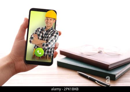 Woman with smartphone calling professional repairman indoors, closeup Stock Photo