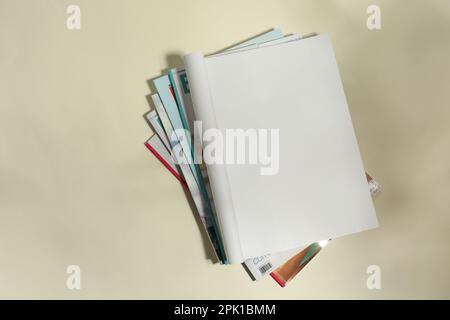 Stack of magazines and one open with blank page on beige background, top view Stock Photo