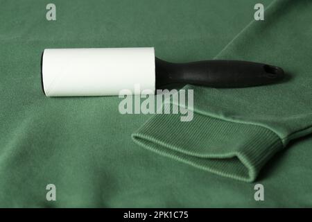 New lint roller with black handle on green sweatshirt Stock Photo