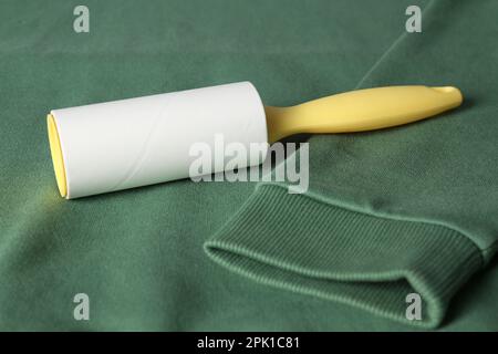 New lint roller with yellow handle on green sweatshirt Stock Photo