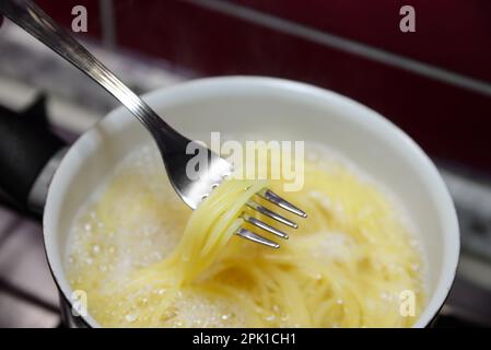 Cooking pasta in saucepan on stove, closeup Stock Photo