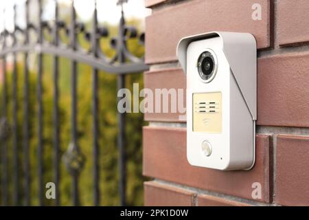 Modern intercom on red wall near gates outdoors, space for text Stock Photo