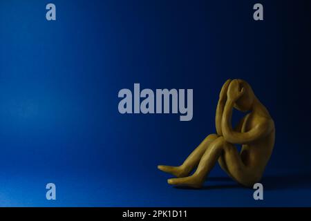 Plasticine figure of crying human on dark blue background. Space for text Stock Photo