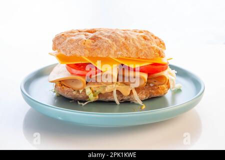 Bologna meat ciabatta sandwich served in a blue plate. Stock Photo