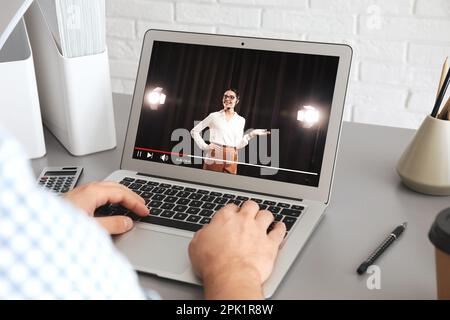 Man watching performance of motivational speaker on laptop at grey table, closeup Stock Photo