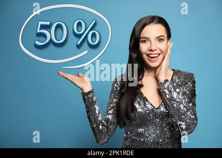 Surprised woman pointing at illustration of fifty percent on light blue background. Special promotion Stock Photo