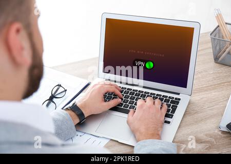 Man using laptop with switched on VPN at table, closeup Stock Photo