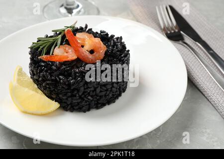 Delicious black risotto with shrimps and lemon on marble table, closeup Stock Photo