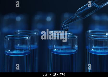 Dripping reagent into test tube with blue liquid on dark background, closeup. Laboratory analysis Stock Photo