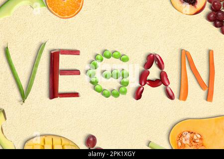 Word VEGAN made of different fresh tasty vegetables on beige background, flat lay Stock Photo