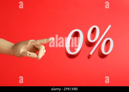 Wooden mannequin hand pointing at sign of zero percent on red background. Special promotion Stock Photo