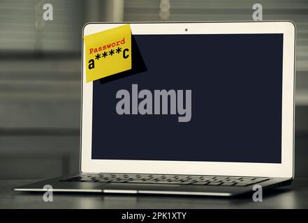 Sticky note with password on laptop indoors. Space for text Stock Photo