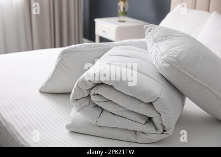Soft folded blanket and pillows on bed indoors Stock Photo