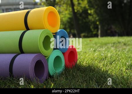 Bright exercise mats on fresh green grass outdoors, space for text Stock Photo