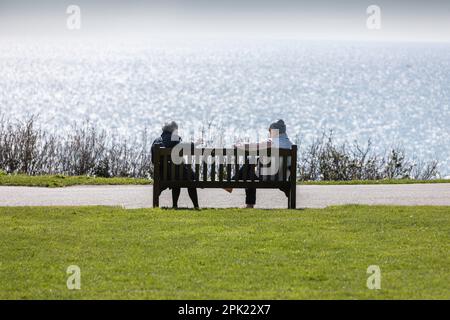 Two men chatting on a bench overlooking the English Channel in Folkestone Stock Photo