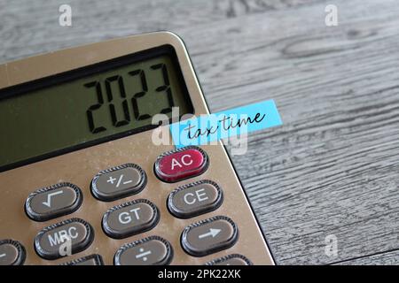 Close up image of calculator with number 2023 on display and sticky note with text TAX TIME. Finance concept Stock Photo
