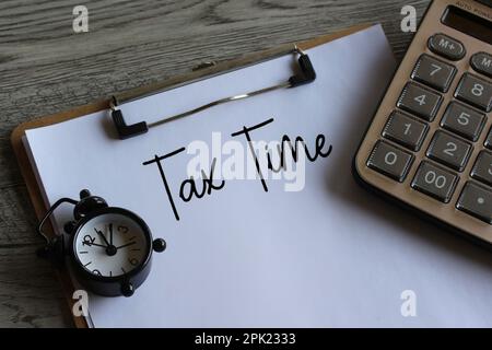Alarm clock and calculator with text TAX TIME. Business and finance concept. Stock Photo