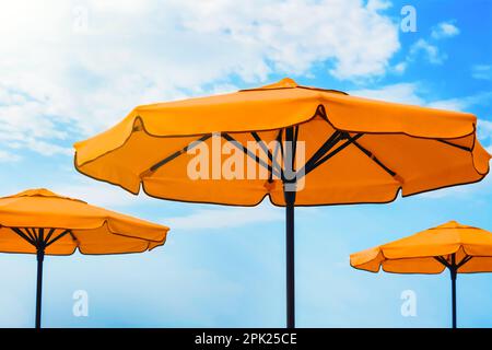 Beautiful orange beach umbrellas against blue sky Stock Photo