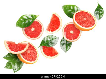 Tasty ripe grapefruits and green leaves falling on white background Stock Photo