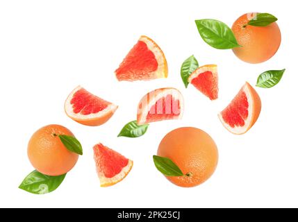 Tasty ripe grapefruits and green leaves falling on white background Stock Photo