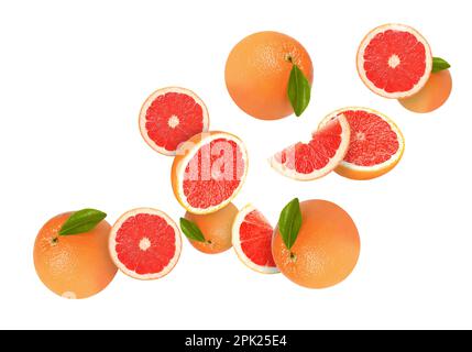 Tasty ripe grapefruits and green leaves falling on white background Stock Photo