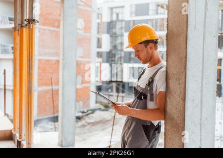 Resting indoors. Young man working in uniform at construction at daytime Stock Photo