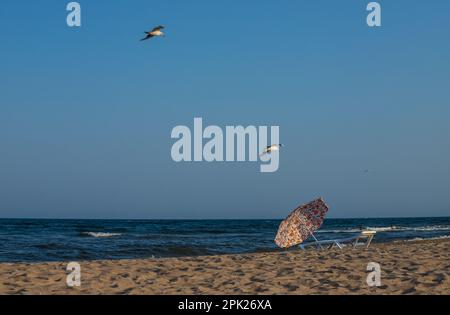 Beach umbrella from the sun and sunbeds are on the beach against the blue sea, sunbeds are towels. Stock Photo
