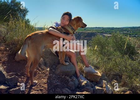 girl hugging a dog after hiking around the mountain in a summer day Stock Photo