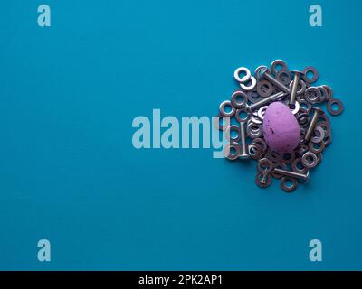 Violet Easter egg on blue background with metal screws Stock Photo