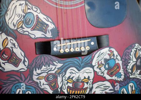 Rather frightening clown faces painted around the bridge of an acoustic guitar Stock Photo