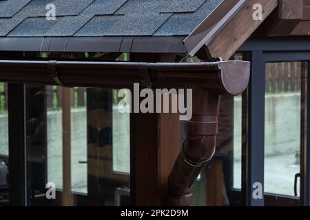 Holder gutter drainage system on the roof. Drain on the roof of the house. Roof drainage. Water drainage from the roof. Stock Photo