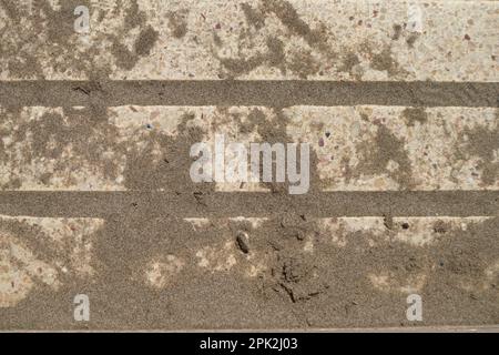 Close-up of the artificial flooring of a sand-filled boardwalk that has brought in the wind from the nearby beach Stock Photo