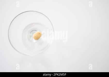 The last mini egg at Easter, one yellow chocolate mini egg shown in a glass bowl on a white background Stock Photo