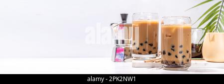 Iced tapioca coffee latte or boba pearl bubbles milk tea, asian trendy cold coffee drink with tapioca balls and crushed ice, on white marble backgroun Stock Photo