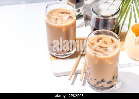 Iced tapioca coffee latte or boba pearl bubbles milk tea, asian trendy cold coffee drink with tapioca balls and crushed ice, on white marble backgroun Stock Photo