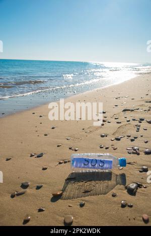 Sea plastic contamination. SOS message in a plastic bottle on the sea shore. Stock Photo