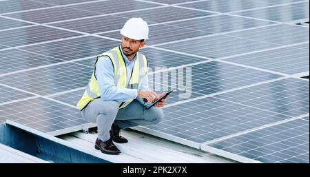 Young engineer or contractor inspecting solar panels on a roof in the city. One confident young manager or maintenance worker smiling while installing Stock Photo