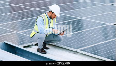 Young engineer or contractor inspecting solar panels on a roof in the city. One confident young manager or maintenance worker smiling while installing Stock Photo