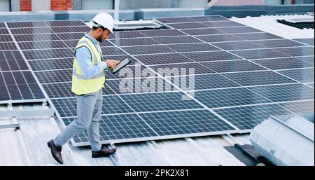 Electrician checking solar panels technology on the roof of the building his working on. Professional engineer technician wearing a safety helmet Stock Photo