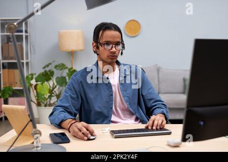Portrait of young black student using computer at home and writing code online Stock Photo