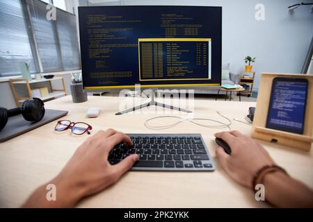 POV of male hands typing at computer keyboard and writing code, copy space Stock Photo
