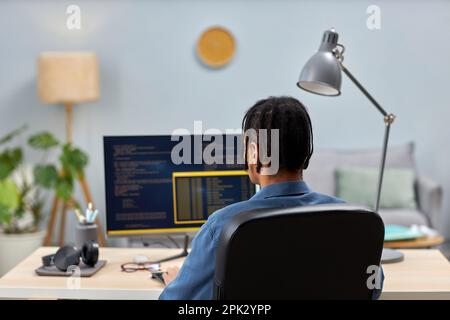 Back view of male IT professional writing code while working at office workplace, copy space Stock Photo