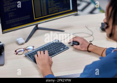 High angle closeup of black young man writing code at workplace and using keyboard, copy space Stock Photo