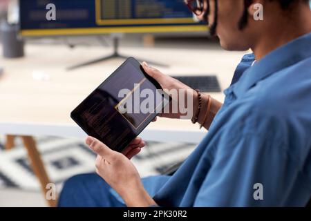 Close up of black computer programmer holding tablet and writing code for mobile devices Stock Photo